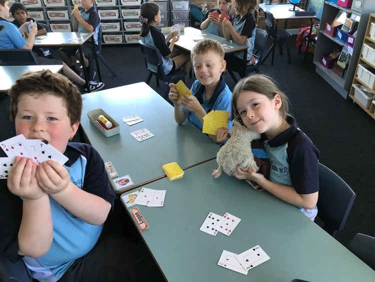 Students playing card games at tables to enhance learning
