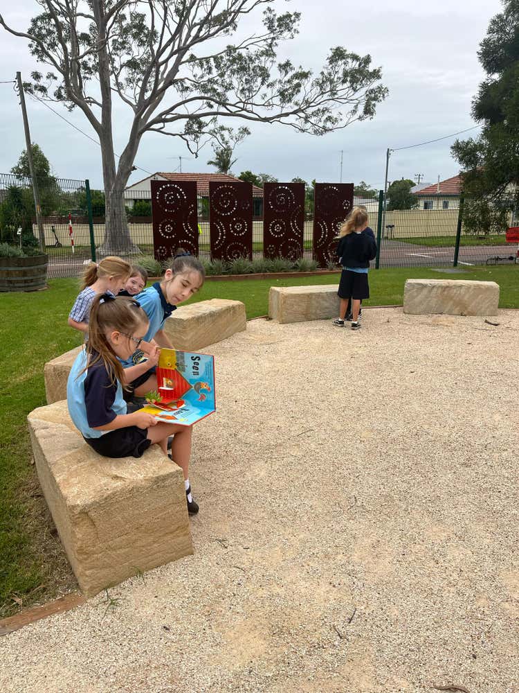 students sitting on sandstone blocks reading